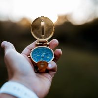 A closeup shot of a person holding a compass with a blurred background
